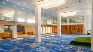 A hotel lobby with a blue carpet, wooden columns, and a chandelier. - Fabhotel Dreams Inn (Thane)