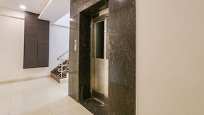 Een moderne lift met een marmeren afwerking, een metalen trap en een paneel dat aan de muur is bevestigd.
