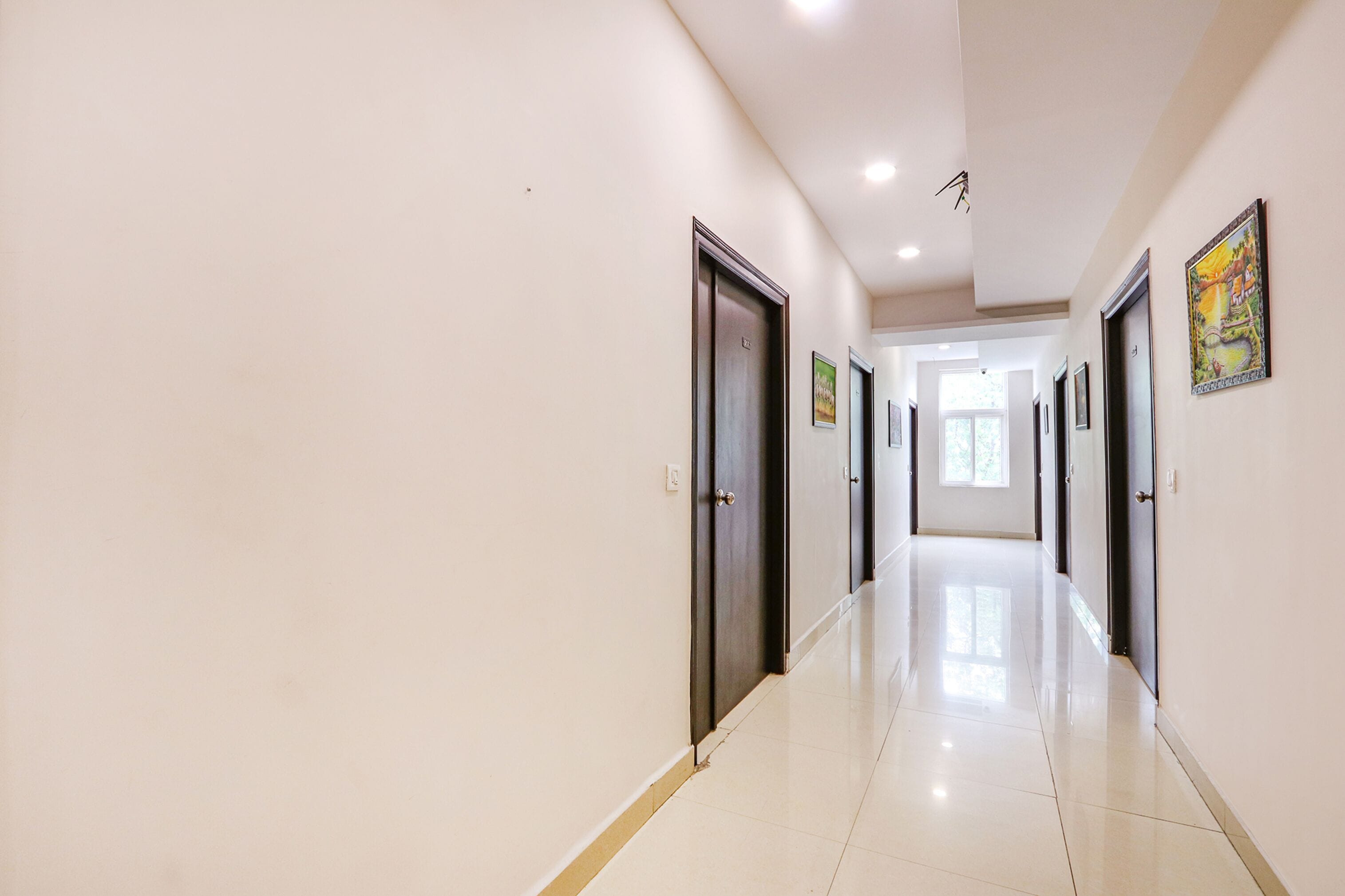 Un pasillo largo e iluminado, con puertas a ambos lados, que conduce a habitaciones.