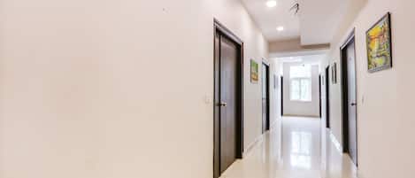 Un pasillo largo e iluminado, con puertas a ambos lados, que conduce a habitaciones.
