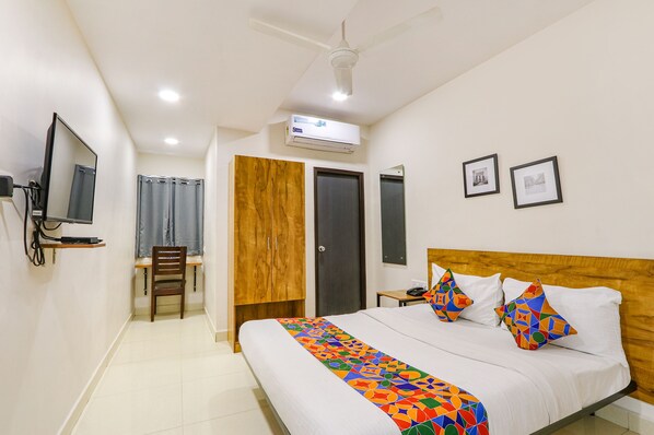 Relax in a stylish room with a large bed, TV, and ceiling fan.