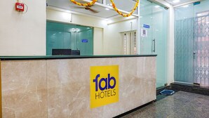 A hotel reception area with a marble counter, a sign for 'fab hotels', and a glass door with a window. - Fabhotel Lake View (Pune)