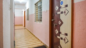 A hallway with a wooden floor, pink walls, and a door marked with the number 202. - Fabhotel Lake View (Pune)