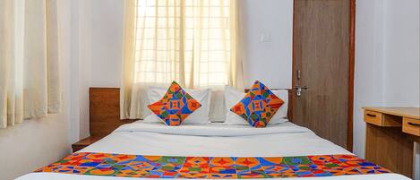 A neatly made bed with a colorful geometric-patterned bedspread and two decorative pillows.