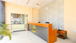A hotel reception area with a wooden reception desk, a clock on the wall, and a reception sign.