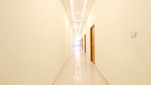 A long, narrow hallway with a series of doors on one side and a light-colored floor.