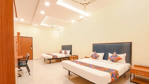 A hotel room with two beds, a desk, and a chair.