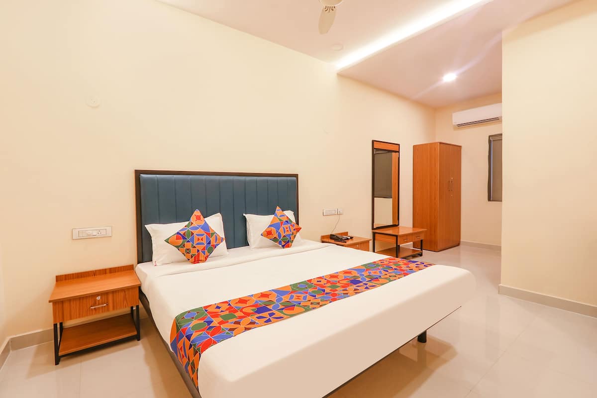 Hotelkamer met een groot bed, een houten nachtkastje, een bureau, een kledingkast en een airconditioner.