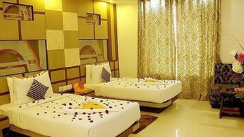 A hotel room with two beds, a large mirror, a decorative wall panel, and a patterned curtain.