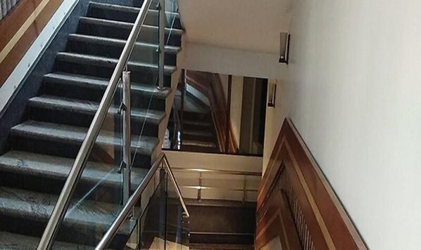 A staircase with a glass railing and wooden trim. - Fabhotel Prime Simna International (Muzaffarpur)