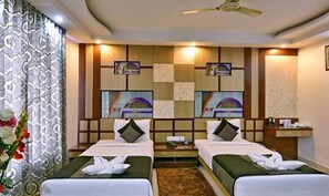 A hotel room with two beds, a ceiling fan, and artwork on the walls. - Fabhotel Prime Simna International (Muzaffarpur)