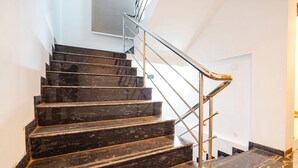 Una escalera con escalones de mármol oscuro y barandilla de metal.