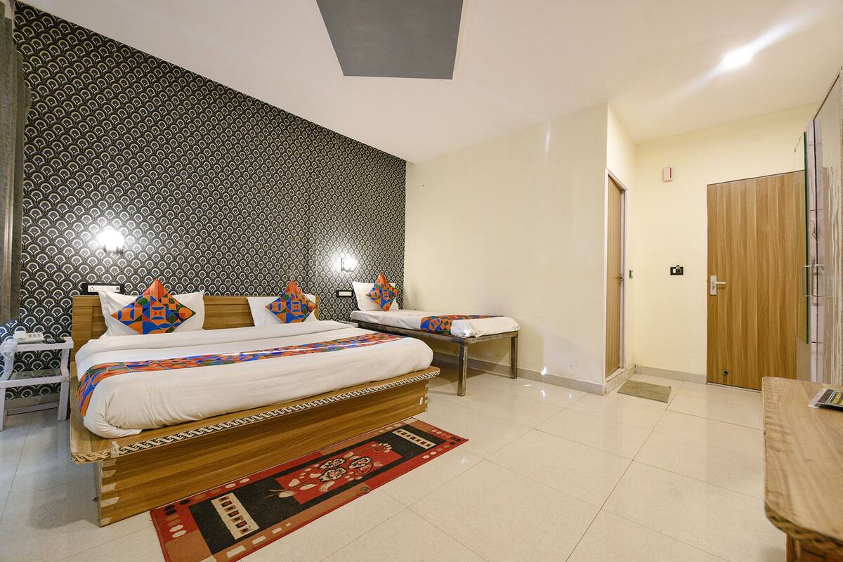 A modern bedroom with a large bed, a smaller bed, and a desk.