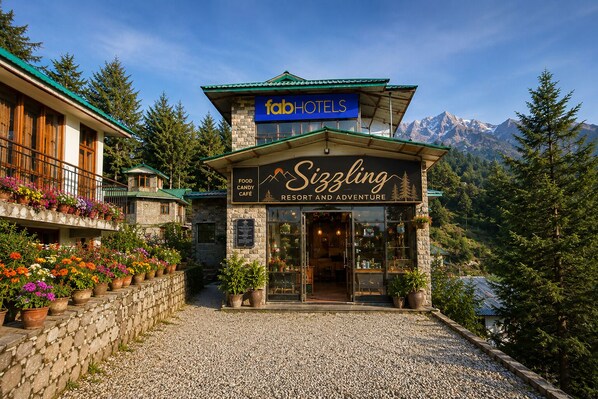 A building with a sign for 'fabHOTELS' and 'Sizzling Resort and Adventure Food Candy Cafe'.