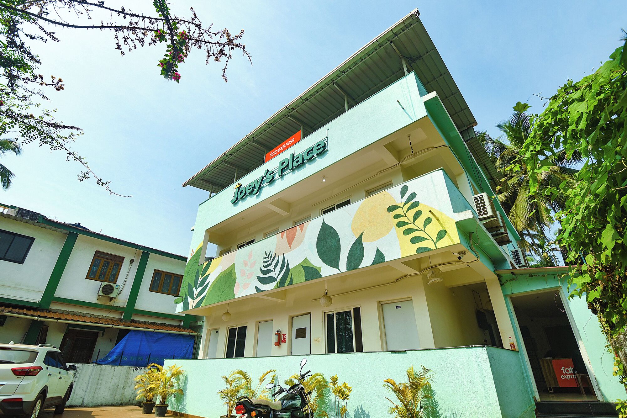 A two-story building with a sign reading "Joey's Place" and a colorful floral mural on the facade.