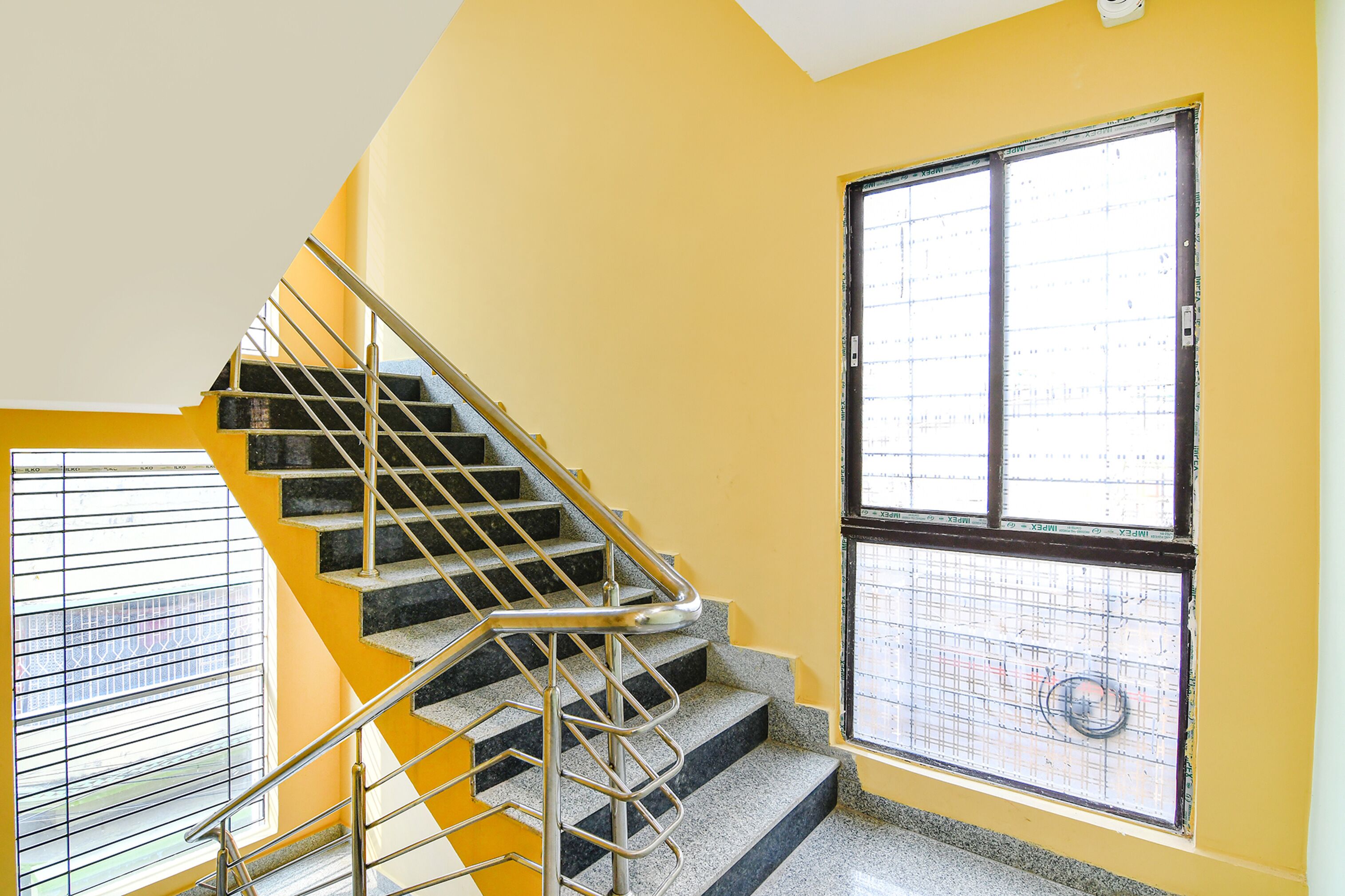 A staircase with metal railings and a window with a grid pattern.