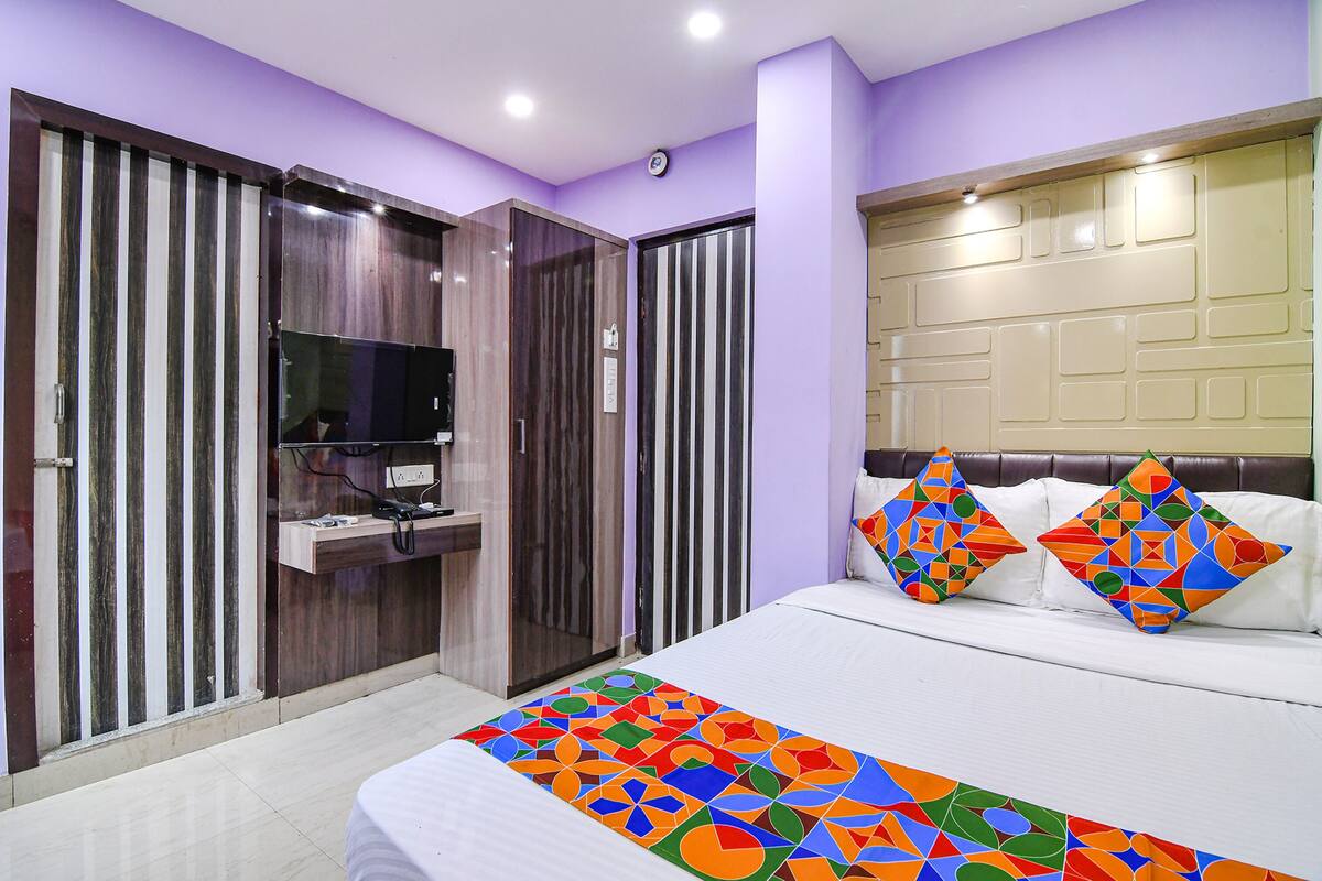 A bedroom with a bed, pillows, a TV, and a wardrobe.