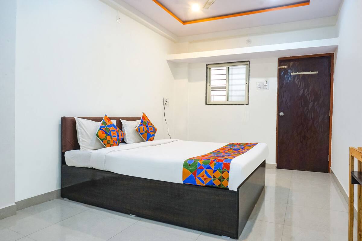 A neatly arranged bedroom with a bed, pillows, a window, and a door.