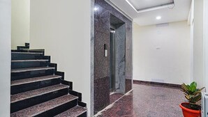 Een modern interieur met een marmeren trap naar een deur, een potplant en een opgeruimde, rustige ruimte.