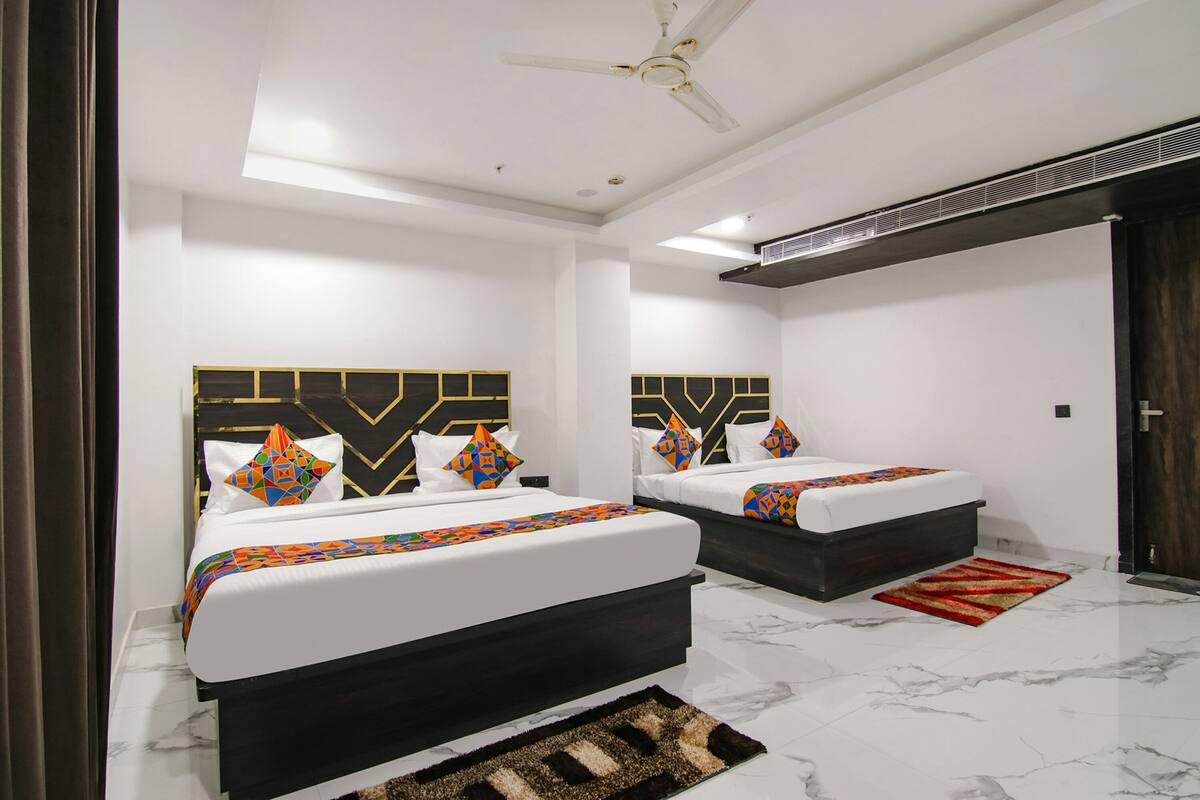 A modern hotel room with two beds, a ceiling fan, and a marble floor.