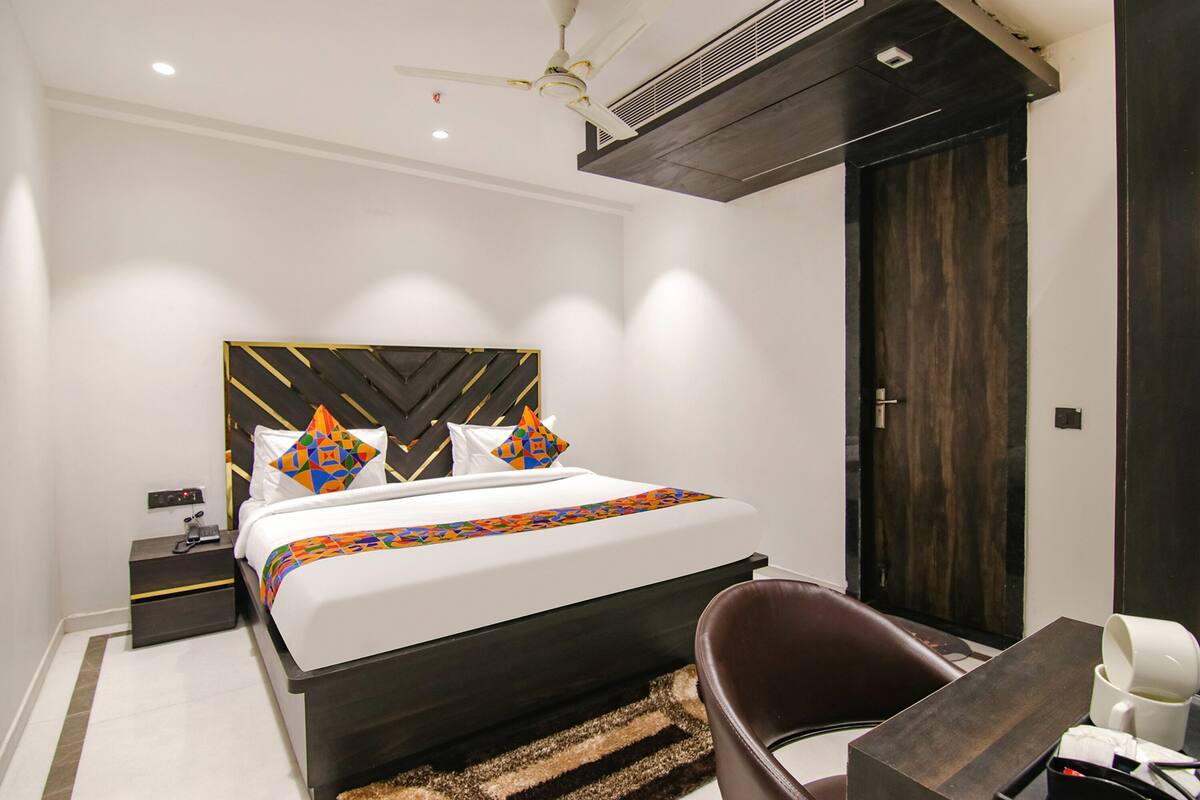 A modern hotel room with a large bed, a desk, and a chair.