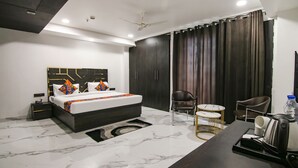 Une chambre d’hôtel moderne avec un grand lit, une armoire en bois foncé, un bureau avec une bouilloire et une chaise.