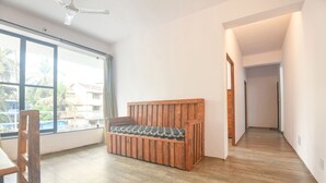 A room with a wooden bench, large windows, and a view of palm trees. - FabHotel Holiday Suites - Nr. Benaulim Beach (Benaulim)