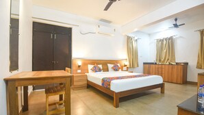 A hotel room with a wooden bed, bedside tables, a wardrobe, and a ceiling fan. - FabHotel Holiday Suites - Nr. Benaulim Beach (Benaulim)