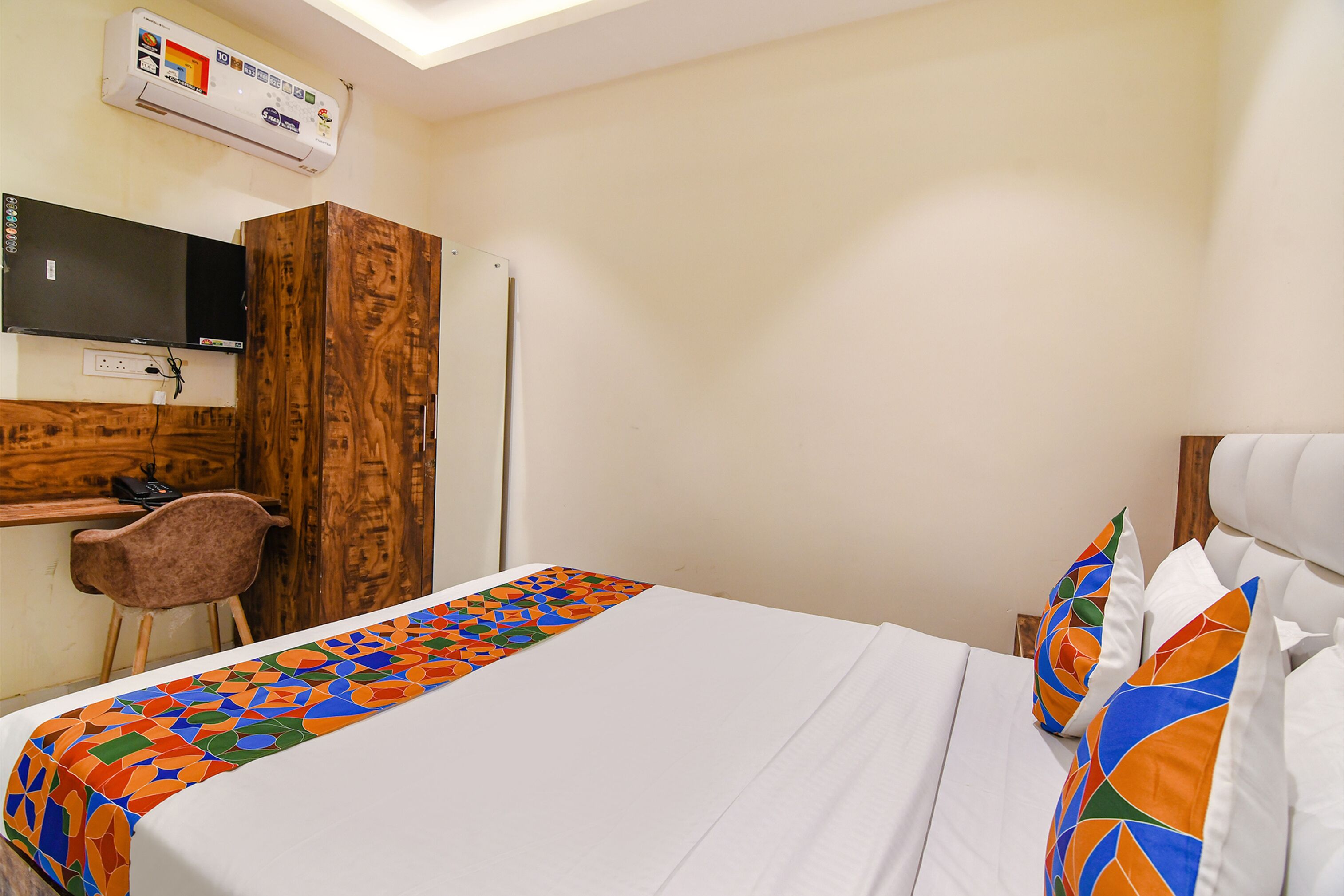 Habitación de hotel con cama, escritorio, silla y televisor.