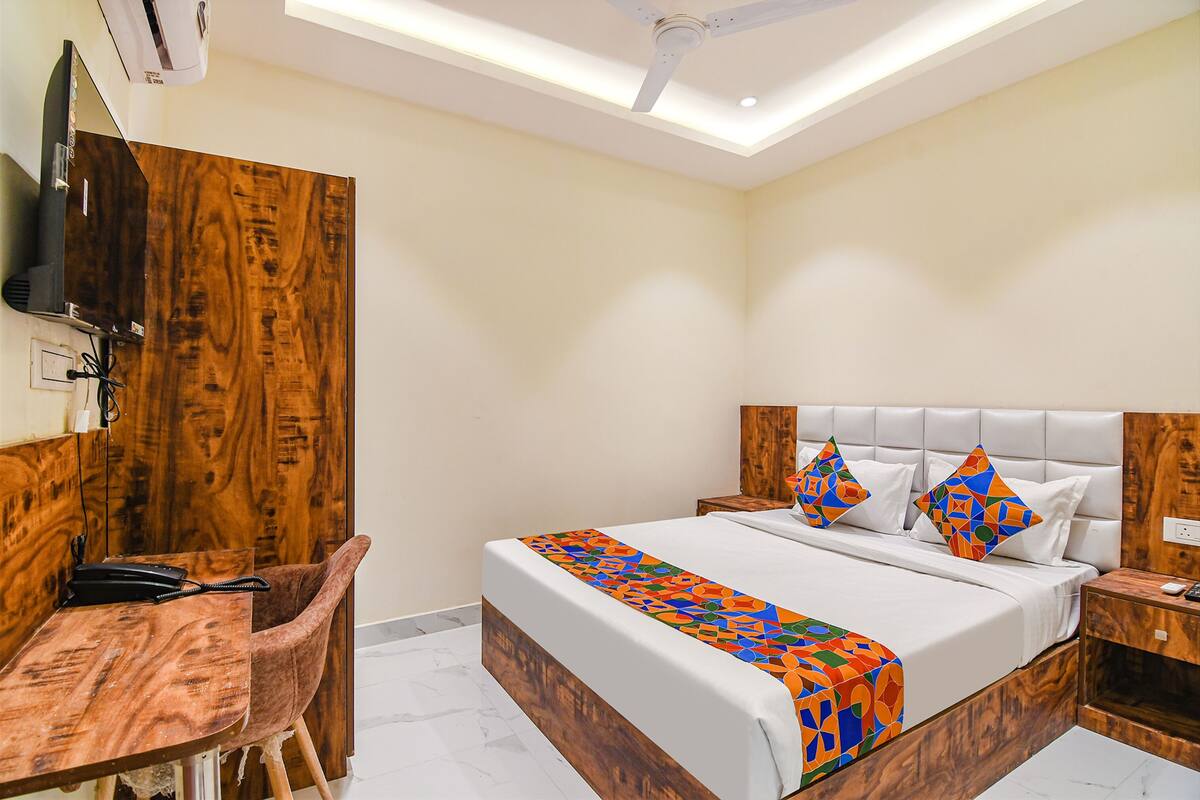 A hotel room with a bed, a desk, a chair, and a ceiling fan.