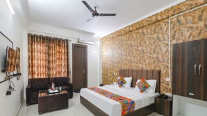 A hotel room with a bed, a sofa, a coffee table, a ceiling fan, and a wardrobe. - Fabhotel The Villa I (Prayagraj)