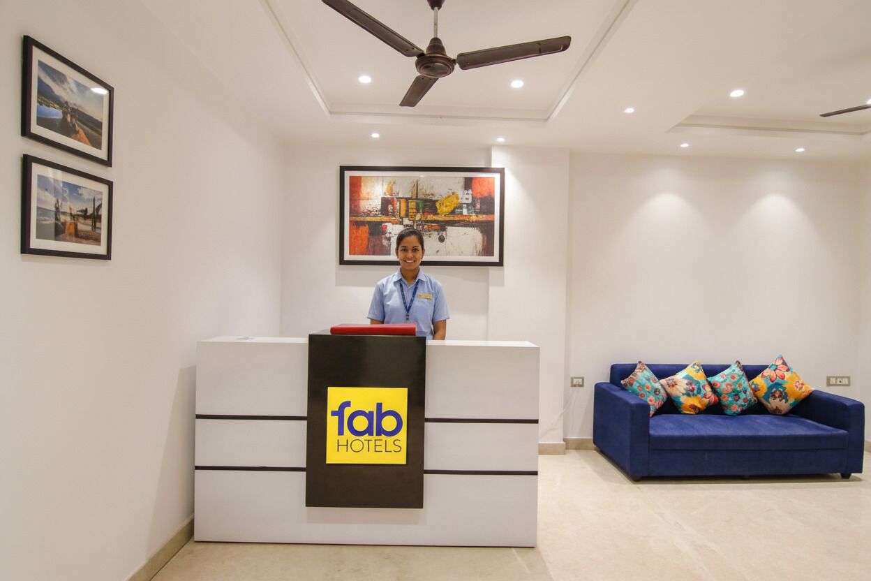 A hotel reception area with a reception desk, a blue sofa, and a ceiling fan.