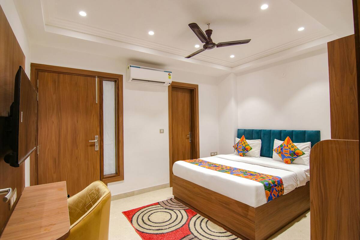 Un dormitorio con cama, escritorio, silla, ventilador de techo y aire acondicionado.