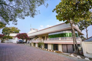 Um hotel de dois andares com varanda, um carro estacionado e uma motocicleta.