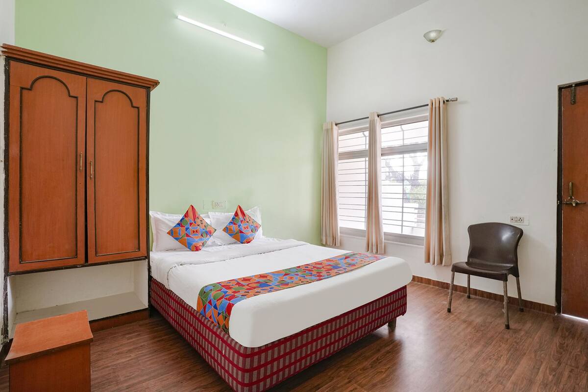 Une chambre à coucher avec un lit, une armoire, une chaise et une fenêtre avec des rideaux.