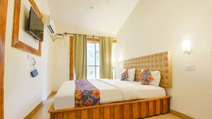 A bedroom with a large bed, wooden headboard, and a window with curtains. - Fabhotel Grand Royal Palms (Benaulim)