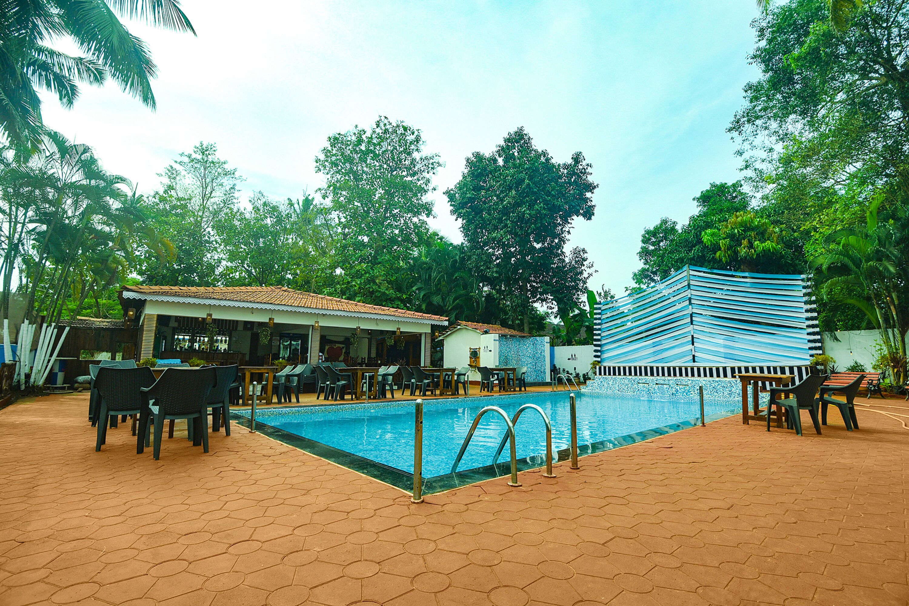 A pool area with hexagonal tiles, lounge chairs, and a building with a tiled roof.
