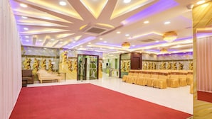 A spacious hall with a red carpet, rows of yellow chairs, and a decorative ceiling with recessed lighting. - Fabhotel Prime Ravila Grand (Hyderabad)