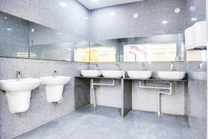 A modern bathroom with four white sinks, a large mirror, and a white hand dryer. - Fabhotel Prime Ravila Grand (Hyderabad)