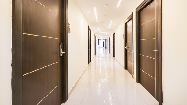 A long, well-lit hallway with dark wooden doors and white walls. - Fabhotel Prime Ravila Grand (Hyderabad)