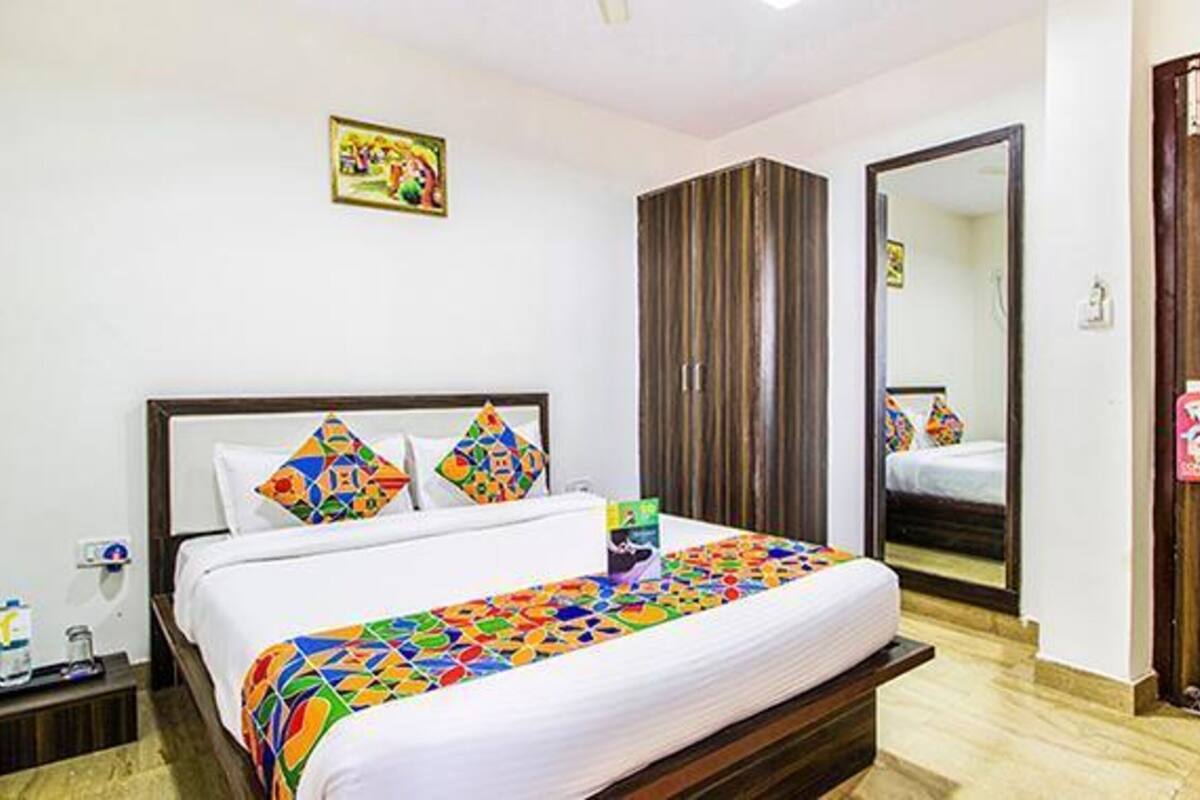 Una habitación de hotel con cama, armario, espejo y un cuadro en la pared.