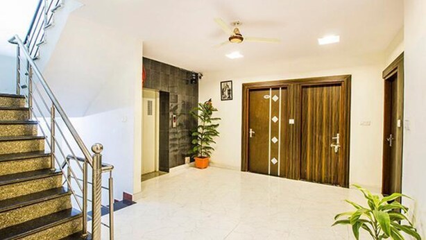 Un hall d’entrée spacieux avec un escalier, un ventilateur de plafond et une plante en pot.