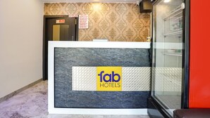 A hotel reception desk with a 'fab hotels' sign, a patterned wall, and a glass display case with shelves. - Fabhotel Sai Vihar (Thane)