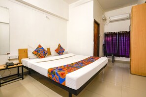 A hotel room with a bed, bedside table, and an air conditioning unit. - Fabhotel Saubhagya Elite (Nashik)
