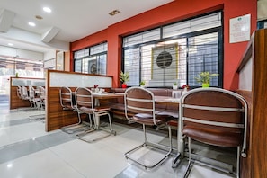 A restaurant with booths and high tables, metal chairs, and potted plants.