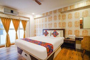 A hotel room with a large bed, a desk with a chair, and a window with curtains. - Fabhotel Prime Signature Inn (Bengaluru)