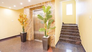 A lobby with a marble wall, an elevator, and a staircase. - Fabhotel Prime Signature Inn (Bengaluru)