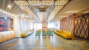A spacious lobby with a patterned floor, green chairs, yellow sofas, and decorative ceiling panels. - Fabhotel Prime Signature Inn (Bengaluru)