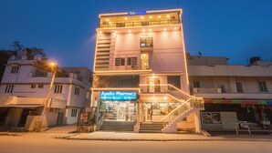 Um edifício de vários andares com uma farmácia no andar térreo, uma escadaria que leva aos andares superiores e uma placa com a inscrição 'Apollo Pharmacy'.
