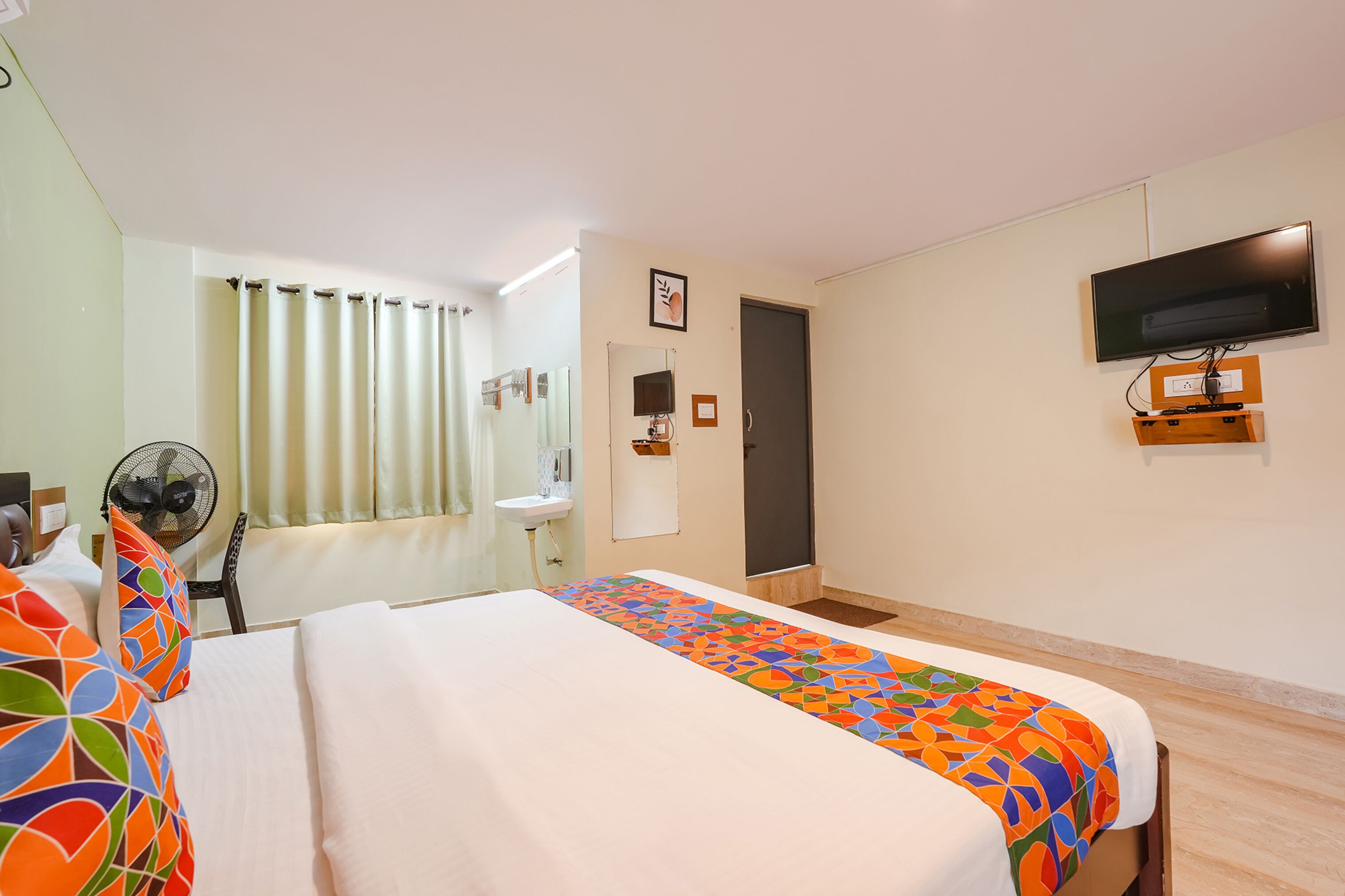 A hotel room with a bed, a desk, a chair, a TV, and a bathroom.